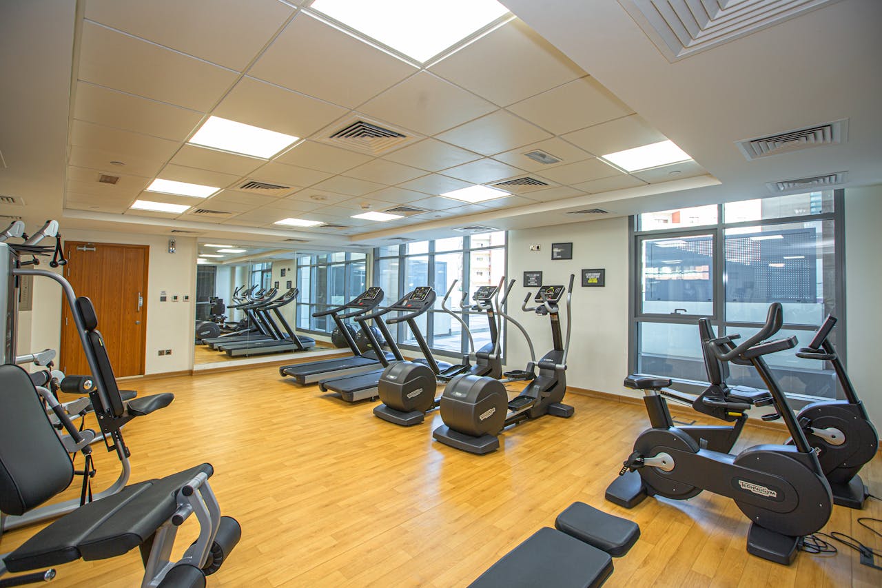 Spacious indoor gym with treadmills, stationary bikes, and exercise equipment on a wooden floor.